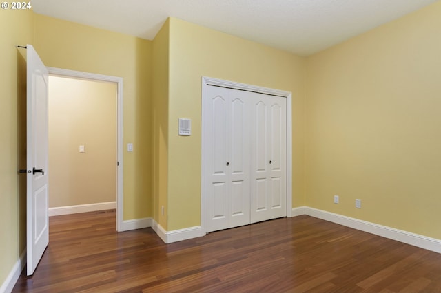 unfurnished bedroom with dark hardwood / wood-style floors and a closet