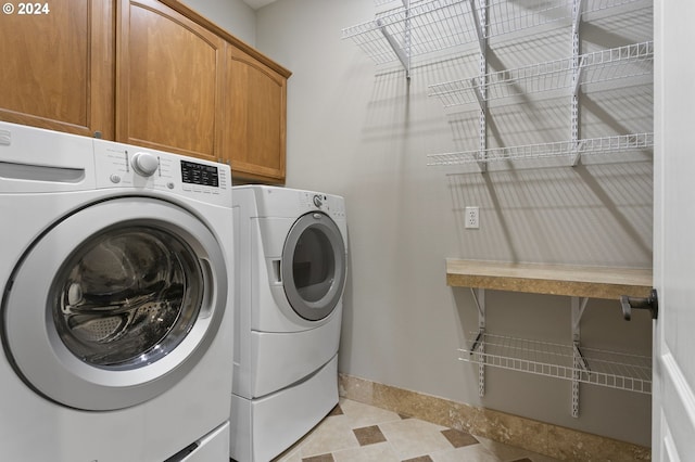 clothes washing area with washing machine and clothes dryer and cabinets