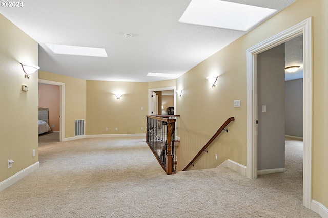 hall featuring light carpet and a skylight