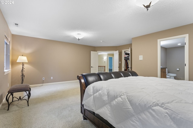 bedroom with ensuite bath, light colored carpet, a textured ceiling, a closet, and a walk in closet