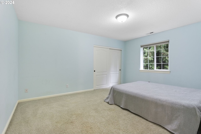 bedroom featuring a textured ceiling, a closet, and carpet floors