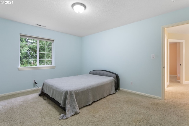 bedroom with light colored carpet and a textured ceiling