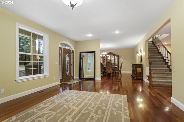 entryway featuring a textured ceiling, dark wood-type flooring, and a chandelier