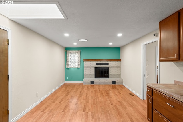 unfurnished living room with a fireplace, light hardwood / wood-style floors, and a textured ceiling