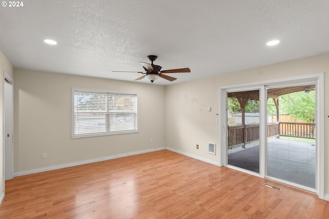 unfurnished room with ceiling fan, a textured ceiling, light hardwood / wood-style flooring, and plenty of natural light