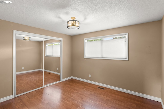 unfurnished bedroom featuring hardwood / wood-style flooring, a closet, and a textured ceiling