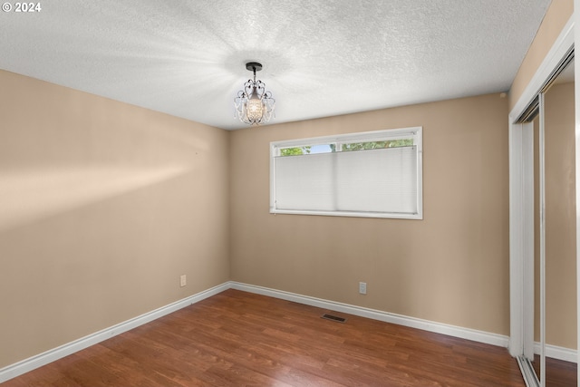 unfurnished bedroom with a closet, hardwood / wood-style floors, a chandelier, and a textured ceiling