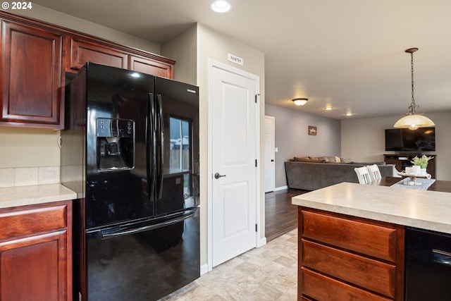 kitchen featuring decorative light fixtures, black refrigerator with ice dispenser, and light hardwood / wood-style flooring