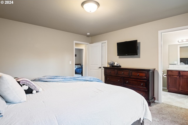 bedroom featuring light carpet and ensuite bath