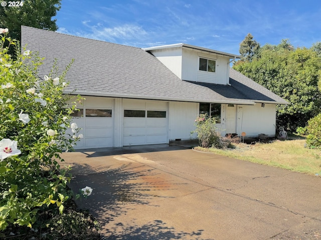 view of front facade featuring an attached garage, a shingled roof, and concrete driveway