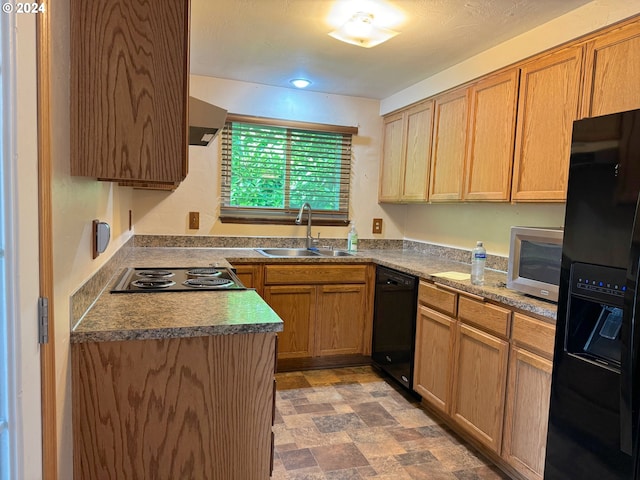 kitchen with black appliances, range hood, and sink