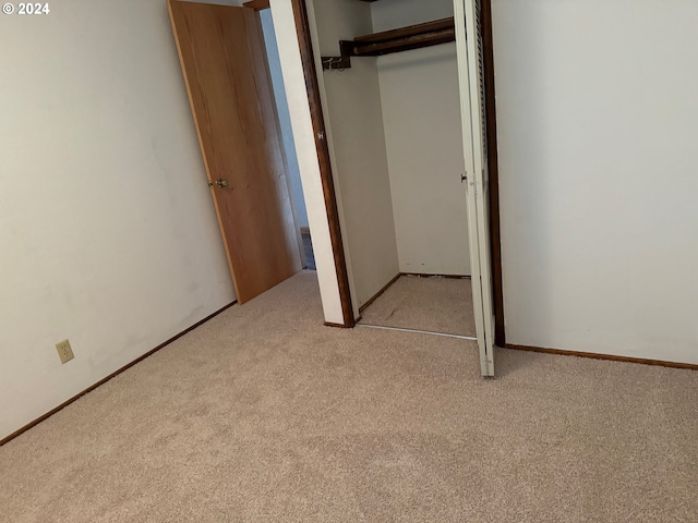 unfurnished bedroom with light colored carpet and a closet