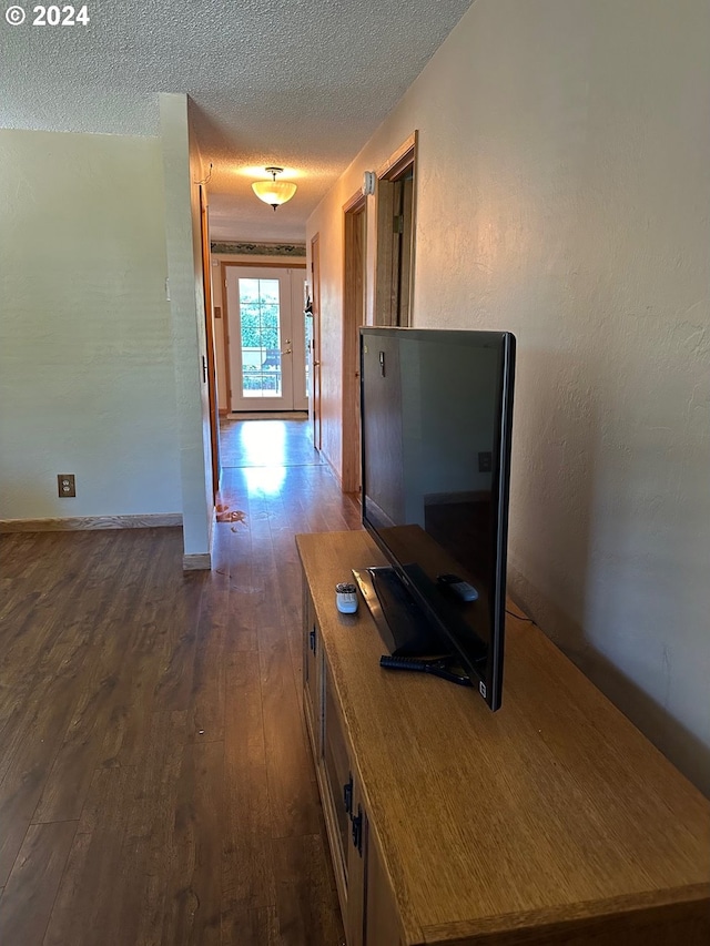 corridor with dark hardwood / wood-style floors and a textured ceiling