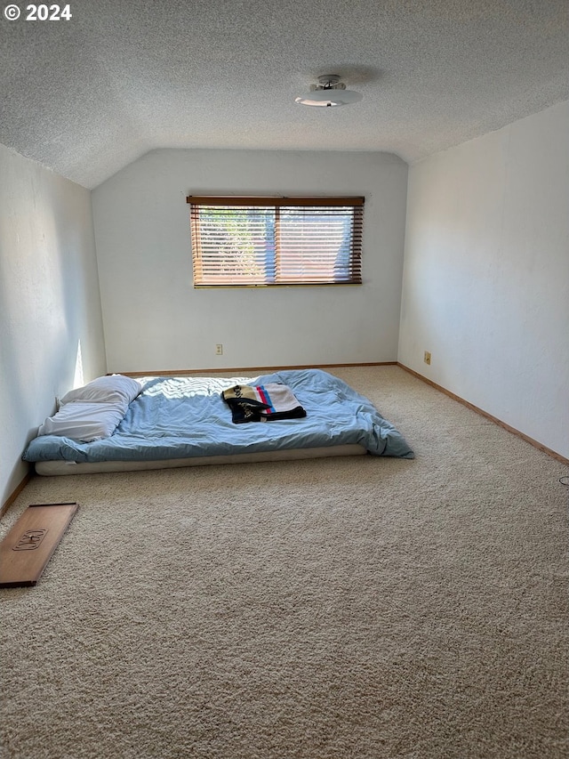 unfurnished bedroom featuring lofted ceiling, a textured ceiling, and carpet floors