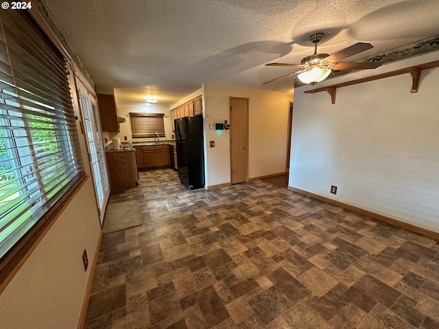 interior space featuring black fridge, a textured ceiling, ceiling fan, and sink