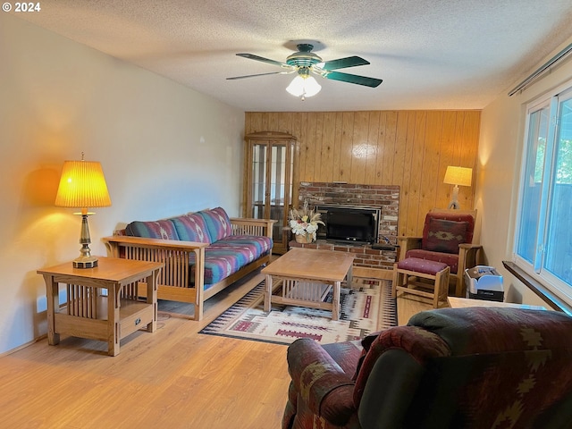 living room featuring a fireplace, a textured ceiling, wood walls, hardwood / wood-style flooring, and ceiling fan