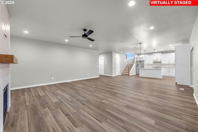 unfurnished living room featuring a fireplace, light wood-type flooring, and ceiling fan