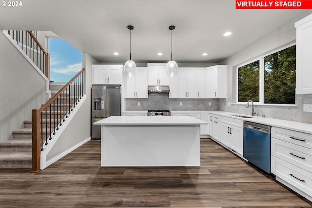 kitchen with appliances with stainless steel finishes, a center island, hanging light fixtures, white cabinetry, and dark hardwood / wood-style floors