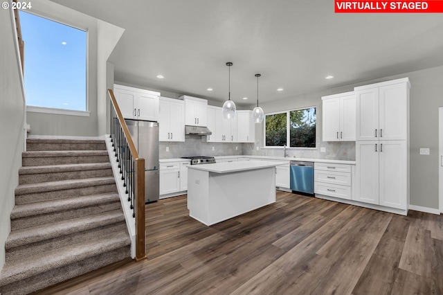 kitchen with appliances with stainless steel finishes, dark hardwood / wood-style flooring, white cabinets, and pendant lighting