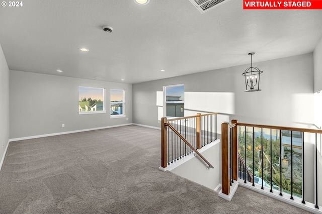 carpeted spare room with a chandelier