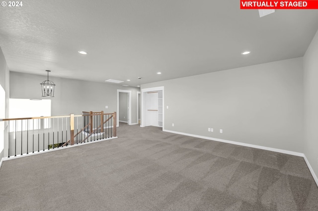 carpeted spare room with an inviting chandelier