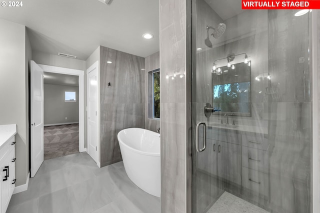 bathroom with a wealth of natural light, vanity, plus walk in shower, and tile walls