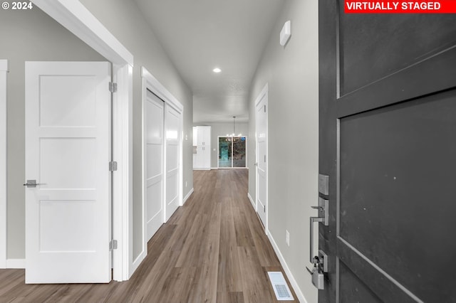 corridor with a chandelier and hardwood / wood-style floors