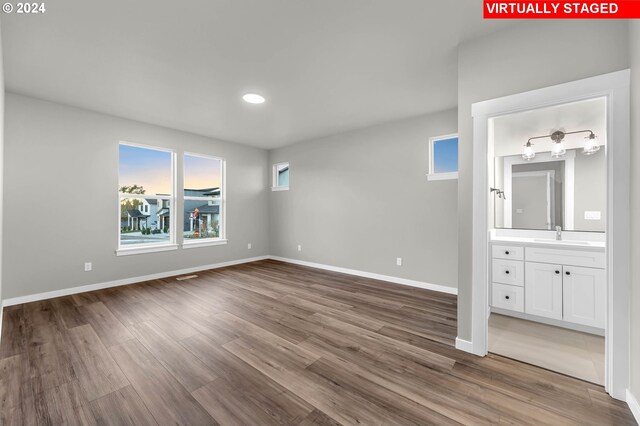 unfurnished bedroom featuring hardwood / wood-style floors, sink, and connected bathroom