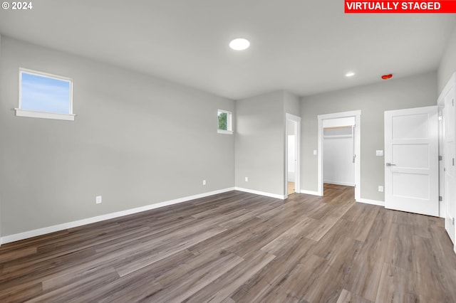 unfurnished bedroom featuring a closet, a spacious closet, and wood-type flooring