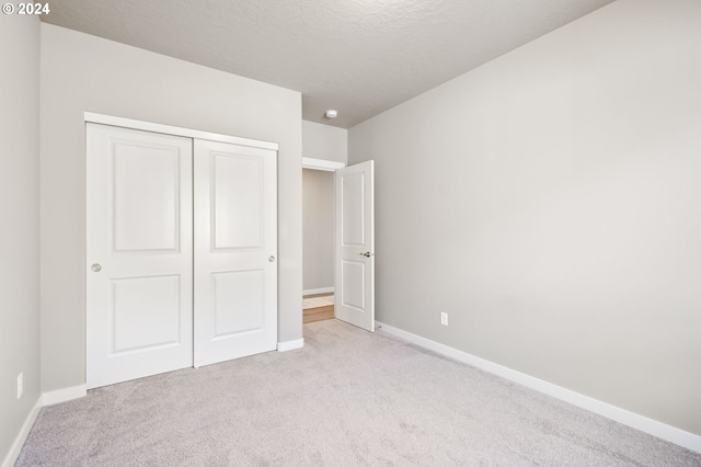 unfurnished bedroom featuring light carpet and a closet