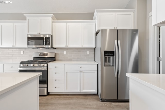 kitchen featuring decorative backsplash, white cabinets, and stainless steel appliances