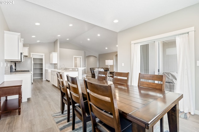 dining room with sink, light hardwood / wood-style flooring, and lofted ceiling