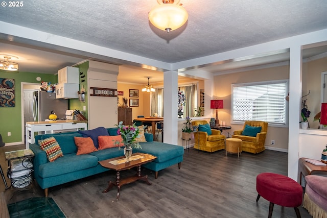 living room featuring a notable chandelier, dark hardwood / wood-style flooring, ornamental molding, and a textured ceiling