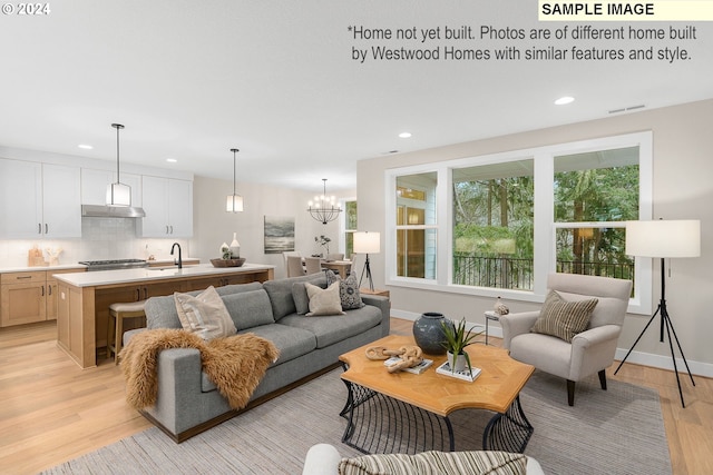 living room featuring light wood-style floors, recessed lighting, visible vents, and an inviting chandelier