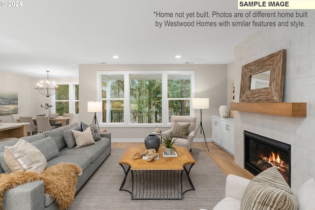 living room with baseboards, recessed lighting, a tiled fireplace, and light wood-style floors