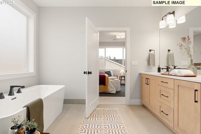 ensuite bathroom featuring baseboards, tile patterned floors, ensuite bathroom, vanity, and a freestanding tub