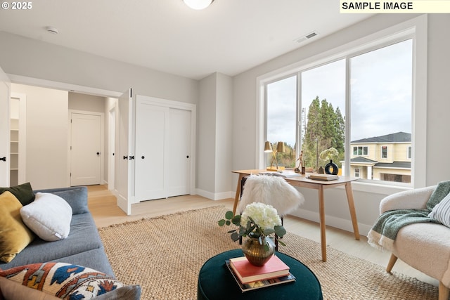 living room with light wood finished floors, baseboards, and visible vents