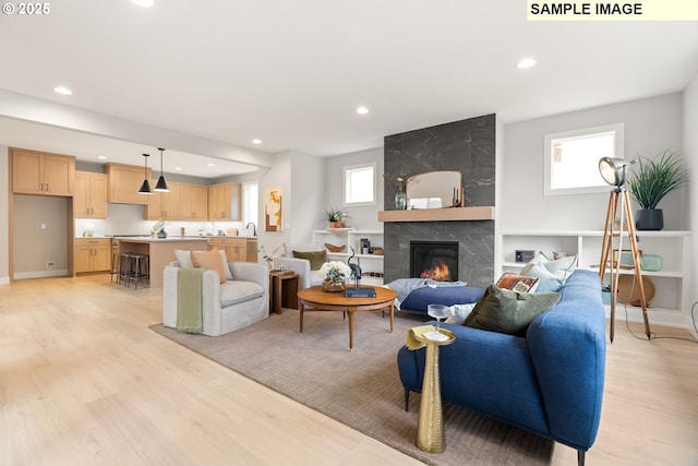 living area featuring a healthy amount of sunlight, light wood finished floors, a fireplace, and recessed lighting