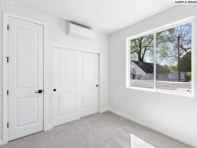 unfurnished bedroom featuring light carpet, a closet, and a wall unit AC