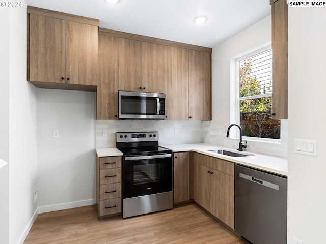 kitchen featuring light hardwood / wood-style floors, appliances with stainless steel finishes, backsplash, and sink