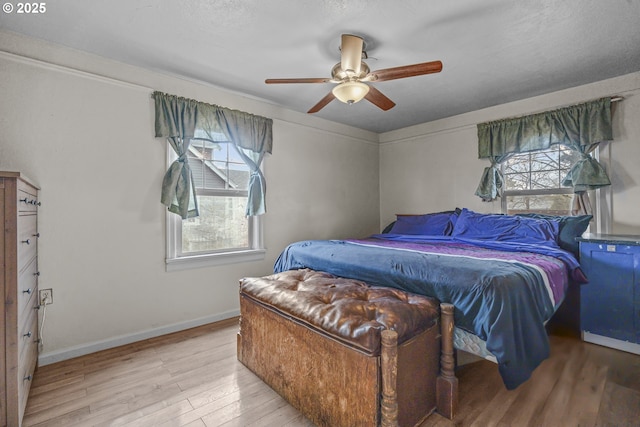 bedroom featuring light wood-type flooring, baseboards, and a ceiling fan