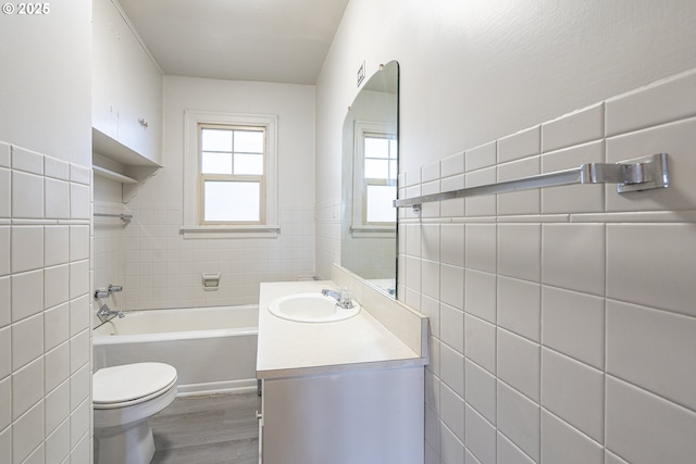 full bathroom with toilet, wood finished floors, vanity, and tile walls