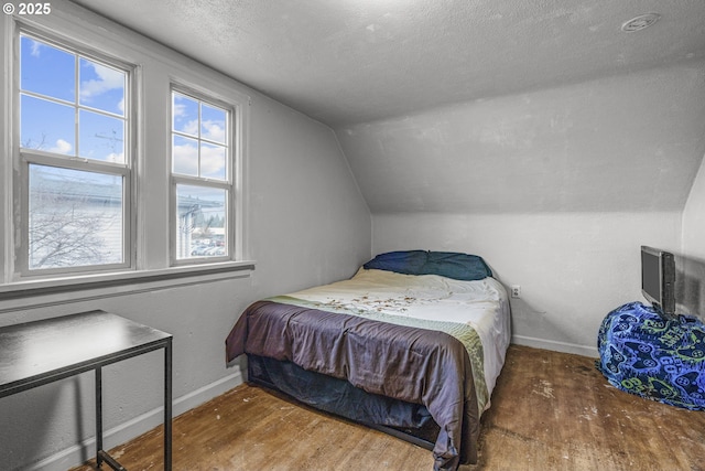 bedroom with lofted ceiling, dark wood finished floors, and baseboards