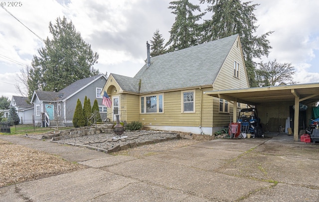 view of front facade with a carport, a shingled roof, and concrete driveway