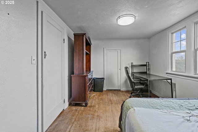 bedroom with light wood-style floors and a textured ceiling