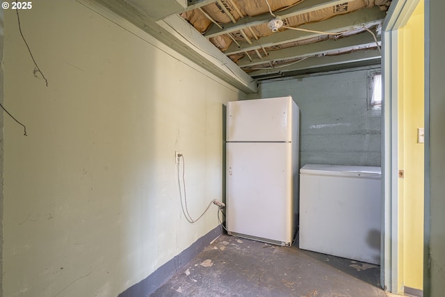 unfinished basement featuring fridge and freestanding refrigerator