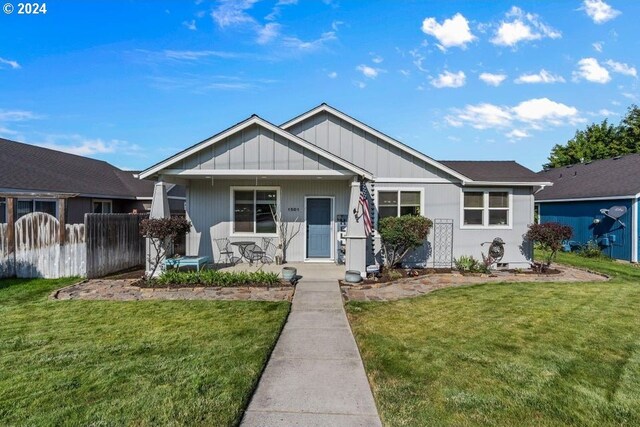 bungalow-style house featuring a porch, fence, and a front yard
