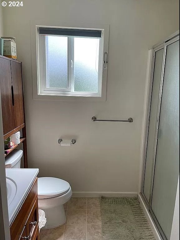 bathroom with vanity, toilet, a shower with shower door, and tile patterned floors