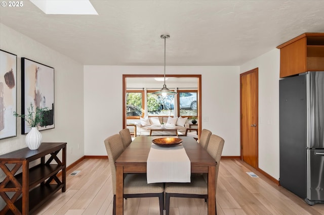 dining space featuring a skylight and light hardwood / wood-style flooring