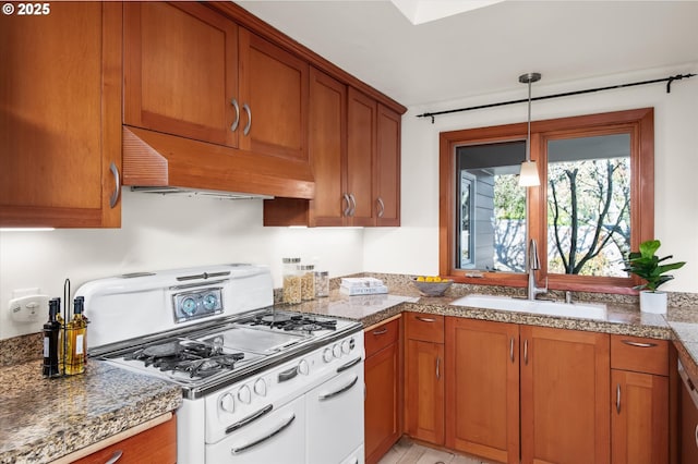 kitchen featuring premium range hood, sink, light stone counters, hanging light fixtures, and white gas range